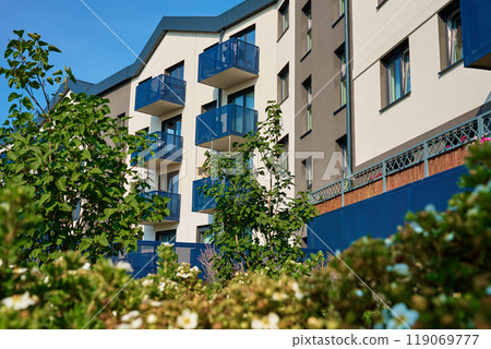 Modern residential apartment building complex exterior with outdoor facilities on sunny summer day. Contemporary real estate architecture 119069777
