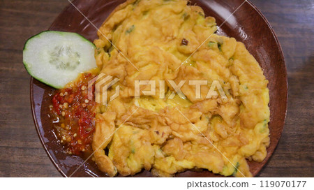 A plate of omelette egg with deep fried cook and traditional sambal or mashed chili sauce. Indonesian style cuisine. 119070177