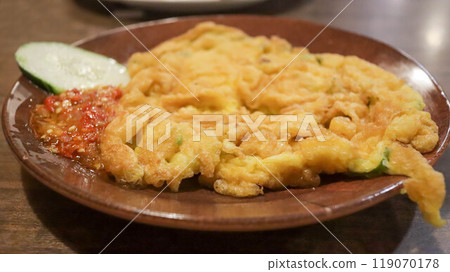 A plate of omelette egg with deep fried cook and traditional sambal or mashed chili sauce. Indonesian style cuisine. A plate of omelette egg with deep fried cook and traditional sambal or mashed chili sauce. Indonesian style cuisine. 119070178