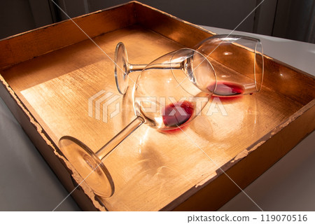 Used wine glasses, two half empty glasses of red wine on a golden tray background Used wine glasses, two half empty glasses of red wine on a golden tray background 119070516