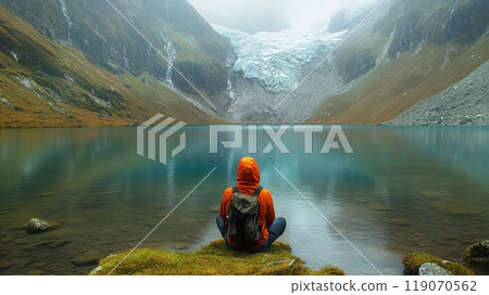 sitting man relaxes against a beautiful natural landscape with mountain lake 119070562
