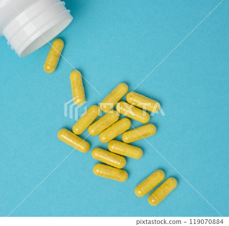 Yellow pills in a capsule on a blue background, pain treatment Yellow pills in a capsule on a blue background, pain treatment 119070884
