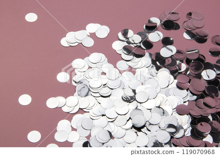 Glittery confetti scattered on a pink background, shiny sparkling glitter for celebration Glittery confetti scattered on a pink background, shiny sparkling glitter for celebration 119070968