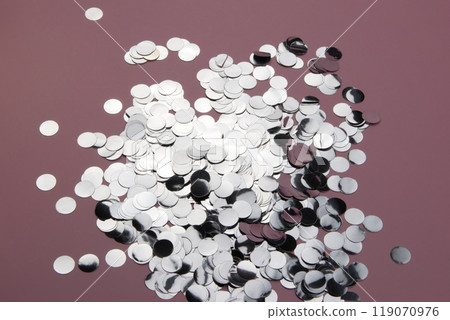 Glittery confetti scattered on a pink background, shiny sparkling glitter for celebration Glittery confetti scattered on a pink background, shiny sparkling glitter for celebration 119070976