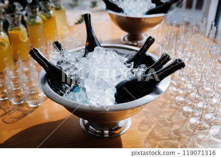Chilled champagne bottles in ice bucket with lemonade pitchers and glasses on the table 119071316