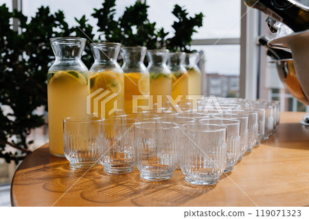Fresh lemonades in glass jugs and empty glasses arranged on a table, summer events or catering Fresh lemonades in glass jugs and empty glasses arranged on a table, summer events or catering 119071323