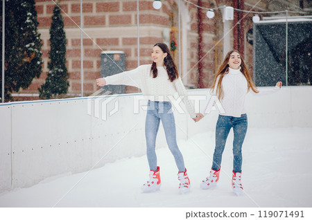 Girls in a winter city. Beautiful ladies in a white sweater. Women in a ice arena 119071491
