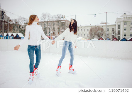 Girls in a winter city. Beautiful ladies in a white sweater. Women in a ice arena 119071492