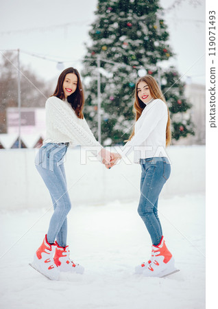 Girls in a winter city. Beautiful ladies in a white sweater. Women in a ice arena 119071493
