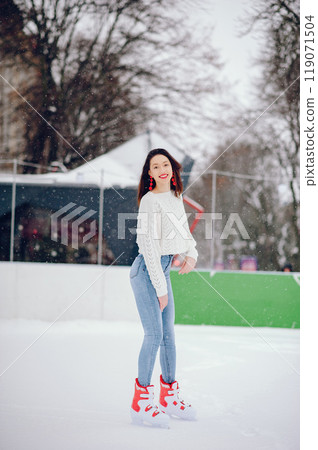 Girl in a winter city. Beautiful lady in a white sweater. Woman in a ice arena 119071504