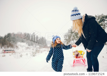 Family have fun in a winter park. Stylish mother in a black jacket. Little girl with pink sled 119071524