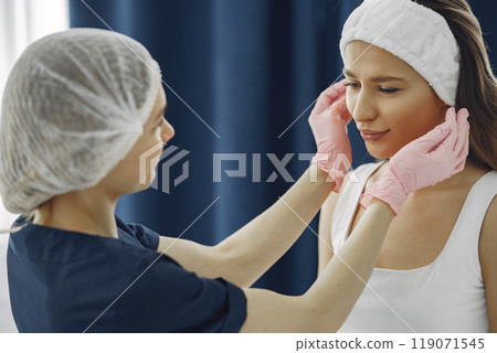 Cosmetologist puts a bandage on the client. Woman with cosmetologist. Lady in a beauty studio. Cosmetologist puts a bandage on the client. Woman with cosmetologist. Lady in a beauty studio. 119071545