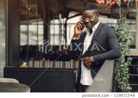 African man. Guy in a black suit. Male with a mobile phone. Businessman at the office. African man. Guy in a black suit. Male with a mobile phone. Businessman at the office. 119071549