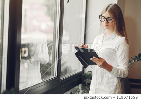 Woman working at the office. Lady with a tablet. Woman in a white blouse. Woman working at the office. Lady with a tablet. Woman in a white blouse. 119071559