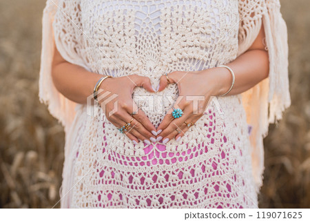 Bohemian Style Dressed Pregnant Boho Woman Holding Heart-Shaped Form On Belly Bohemian Style Dressed Pregnant Boho Woman Holding Heart-Shaped Form On Belly 119071625