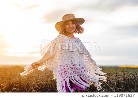 Boho Rustic Styled Woman In Straw Hat dancing In Wheat Field. Golden Hour 119071627