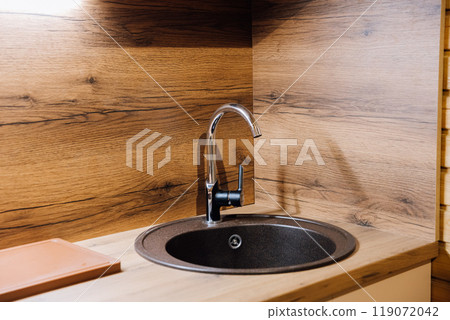 Modern kitchen sink with wooden countertop, showcasing contemporary design and minimalist style 119072042