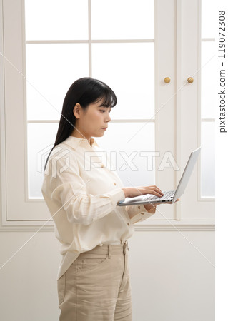 一位女士站著操作筆記型電腦 119072308