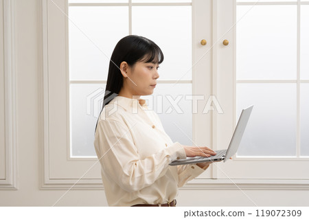 一位女士站著操作筆記型電腦 119072309