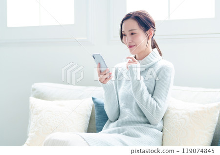 A woman using a smartphone in the living room A woman using a smartphone in the living room 119074845
