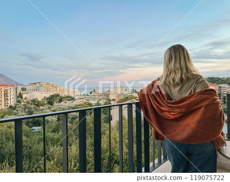 A woman standing on the balcony at summer sunset A woman standing on the balcony at summer sunset 119075722
