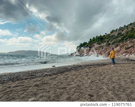 Woman in yellow windbreaker on empty beach Woman in yellow windbreaker on empty beach 119075761