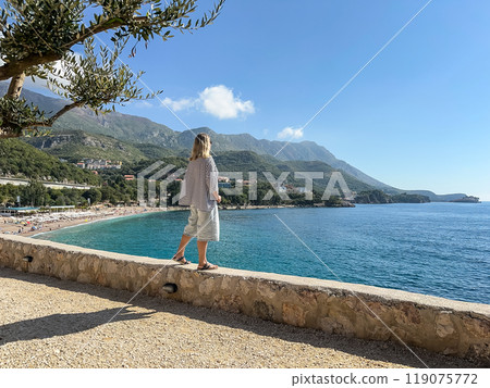 A woman  looks out from a cliff at the sea 119075772