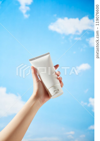 The template image used for advertising skincare products features a strong female model holding a white tube of unlabeled cream under a beautiful blue sky with gently drifting clouds. 119076600