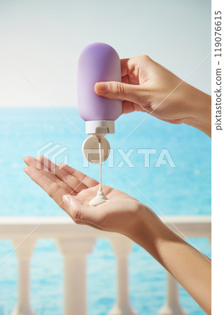 A female model hands-squeezing an unbranded purple tube of cream into a hand is perfect for a sunscreen advertisement image on a balcony overlooking the ocean under a sunny blue sky background. A female model hands-squeezing an unbranded purple tube of cream into a hand is perfect for a sunscreen advertisement image on a balcony overlooking the ocean under a sunny blue sky background. 119076615