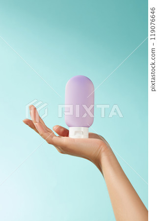 A hand held a mockup purple lotion bottle against a turquoise backdrop. The contrasting colors add a pop of emphasis on the uniqueness of the product, perfect for the advertisement image template. A hand held a mockup purple lotion bottle against a turquoise backdrop. The contrasting colors add a pop of emphasis on the uniqueness of the product, perfect for the advertisement image template. 119076646