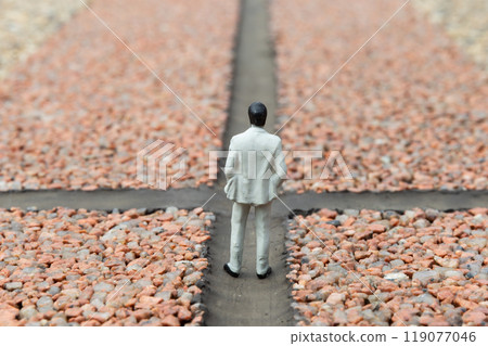 十字路口:穿著西裝的男性娃娃站在生活與事業的十字路口。 十字路口:穿著西裝的男性娃娃站在生活與事業的十字路口。 119077046