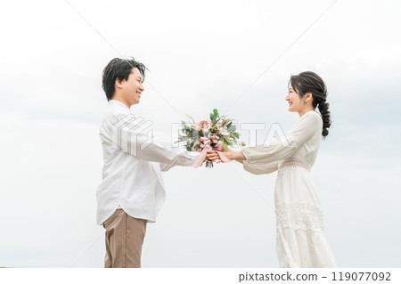 Groom handing over a bouquet and bride receiving it, casual wedding, couple, lovers, married couple image 119077092