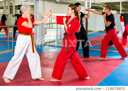 Elderly woman sparring with girl during martial arts training Elderly woman sparring with girl during martial arts training 119078853