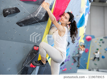 Young woman doing rock climbing on climbing wall 119078915
