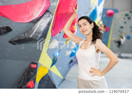 Young woman posing at climbing wall Young woman posing at climbing wall 119078917