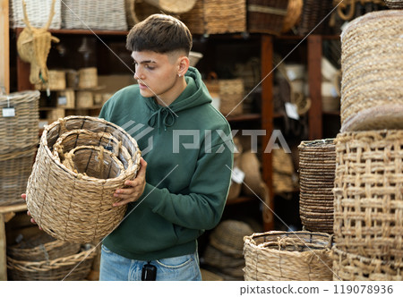 Guy looks at wicker basket in furniture store. 119078936