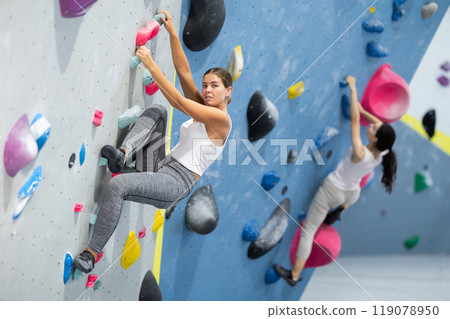 Sportive woman climbing on artificial rock wall in rock climbing gym 119078950