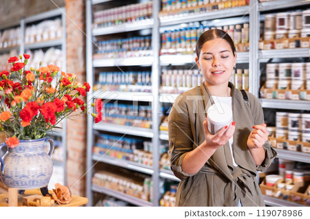 Young woman chooses bottles of paint in shop 119078986