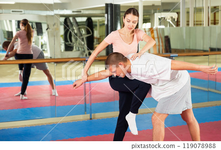 Girl performing knee kick with wrist lock to male opponent in self defense training Girl performing knee kick with wrist lock to male opponent in self defense training 119078988