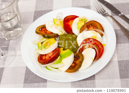 Caprese salad with avocado and pesto sauce 119078991