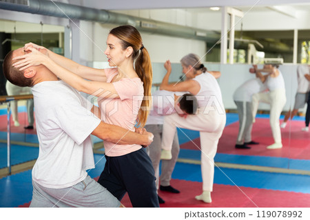 Self-defense course - woman strikes painful blow in the eyes of man 119078992