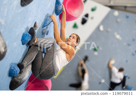 Young woman practicing rock climbing on climbing wall Young woman practicing rock climbing on climbing wall 119079011