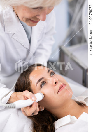 Young woman having face radiolifting procedure made by doctor 119079073
