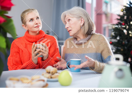 Mature mother and her adult daughter drink tea and chat 119079074