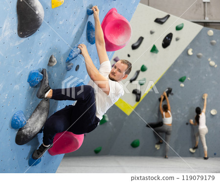 Young man practicing rock climbing on climbing wall Young man practicing rock climbing on climbing wall 119079179
