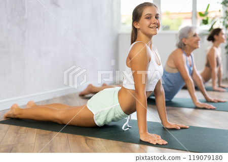 Teenage girl doing Urdhva Mukha Shvanasana during group yoga workout 119079180
