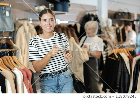 Girl buyer noticed desired product in clothes store and happily smiles from upcoming purchase 119079243