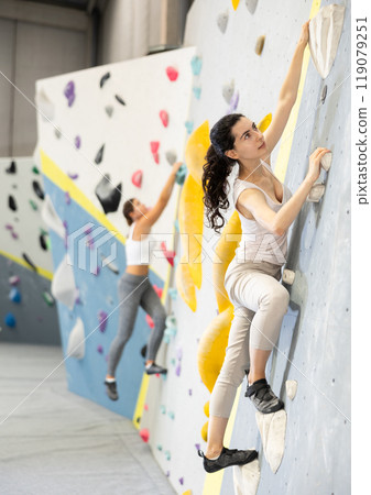 Young woman doing rock climbing on climbing wall 119079251