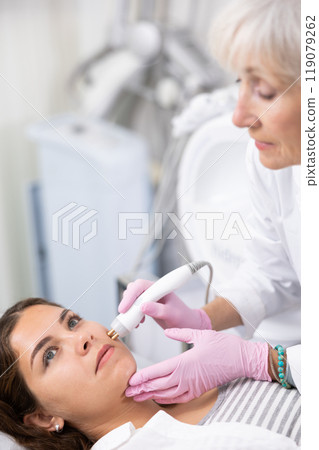 Young woman having face radiolifting procedure made by doctor Young woman having face radiolifting procedure made by doctor 119079262