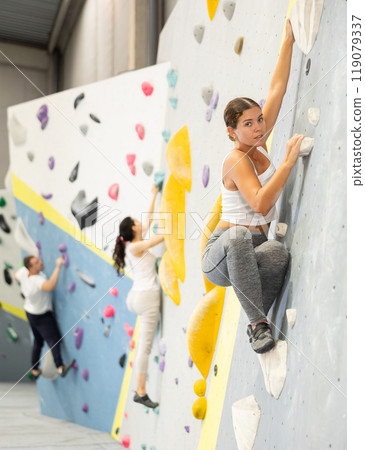 Young woman practicing rock climbing on climbing wall 119079337